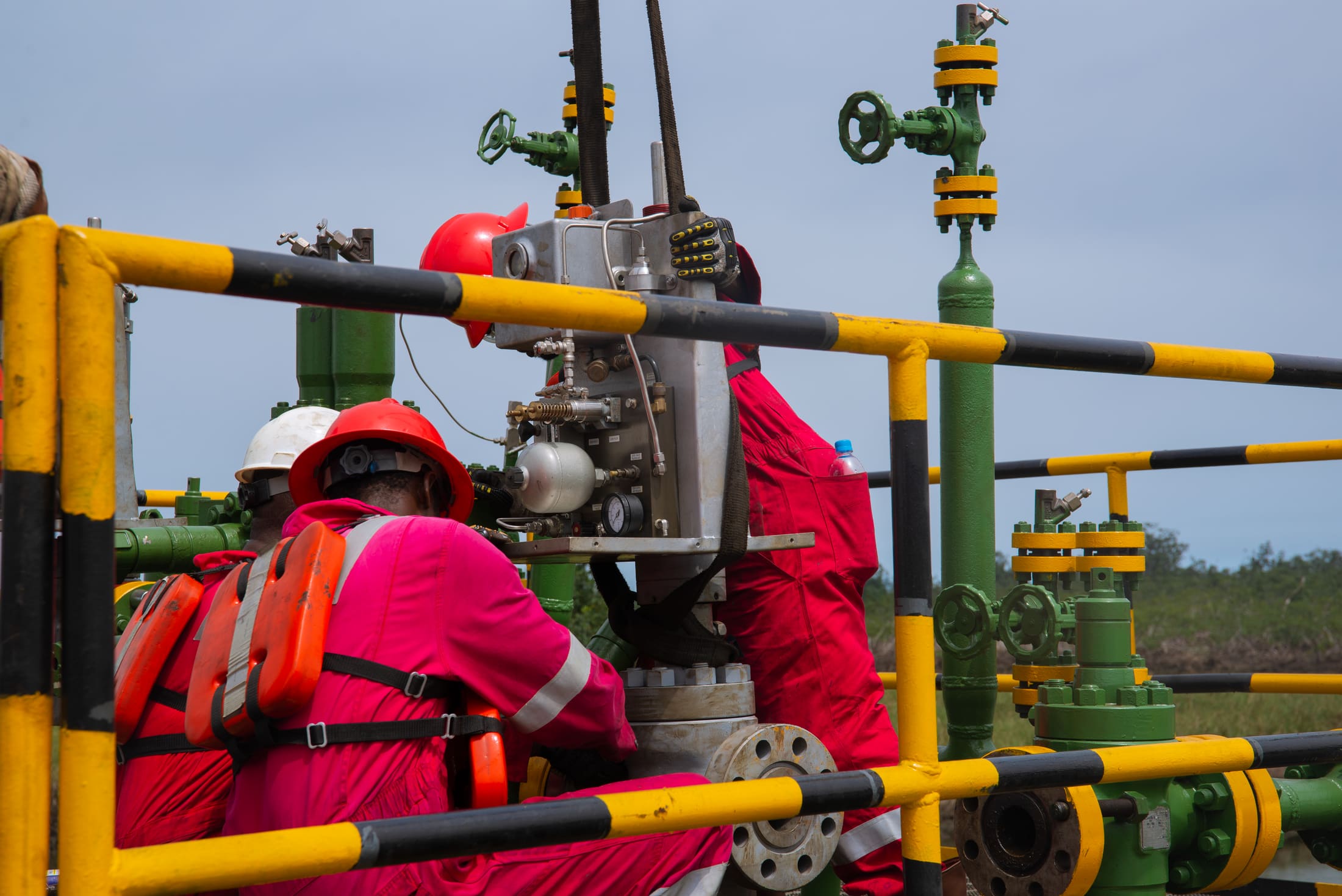 Close coordination between two technicians installing wellhead equipment