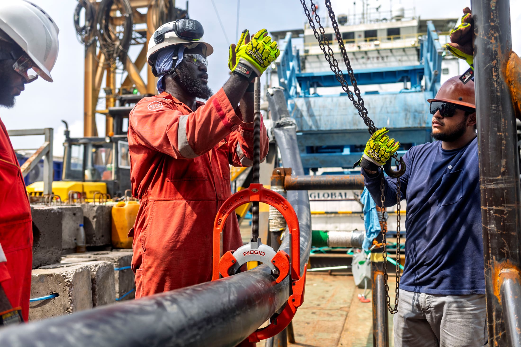 Technicians fitting a hydraulic crimping tool onto pipeline tubing
