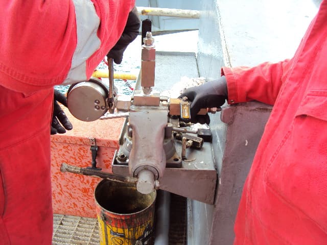 Technicians working closely on a mechanical pressure-control fitting