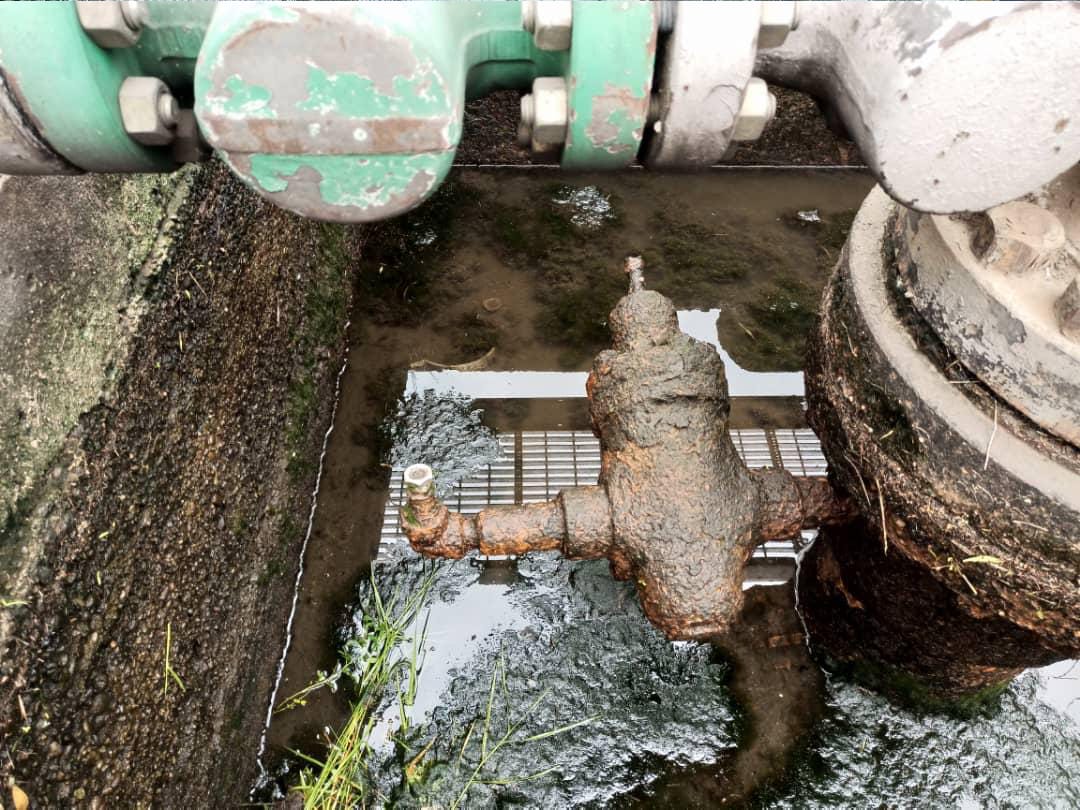 A technician working a wellhead platform with a gate valve tapping tool in the foreground