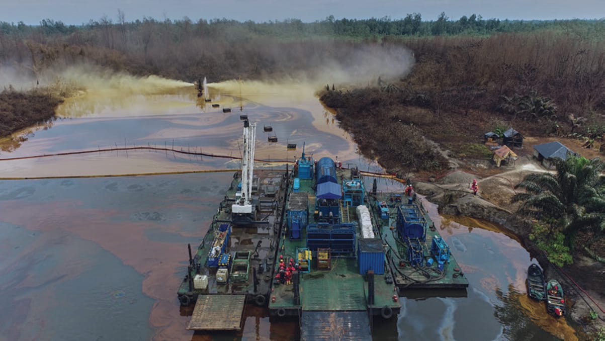 Aerial view of a response barge working alongside containment booms on a waterway