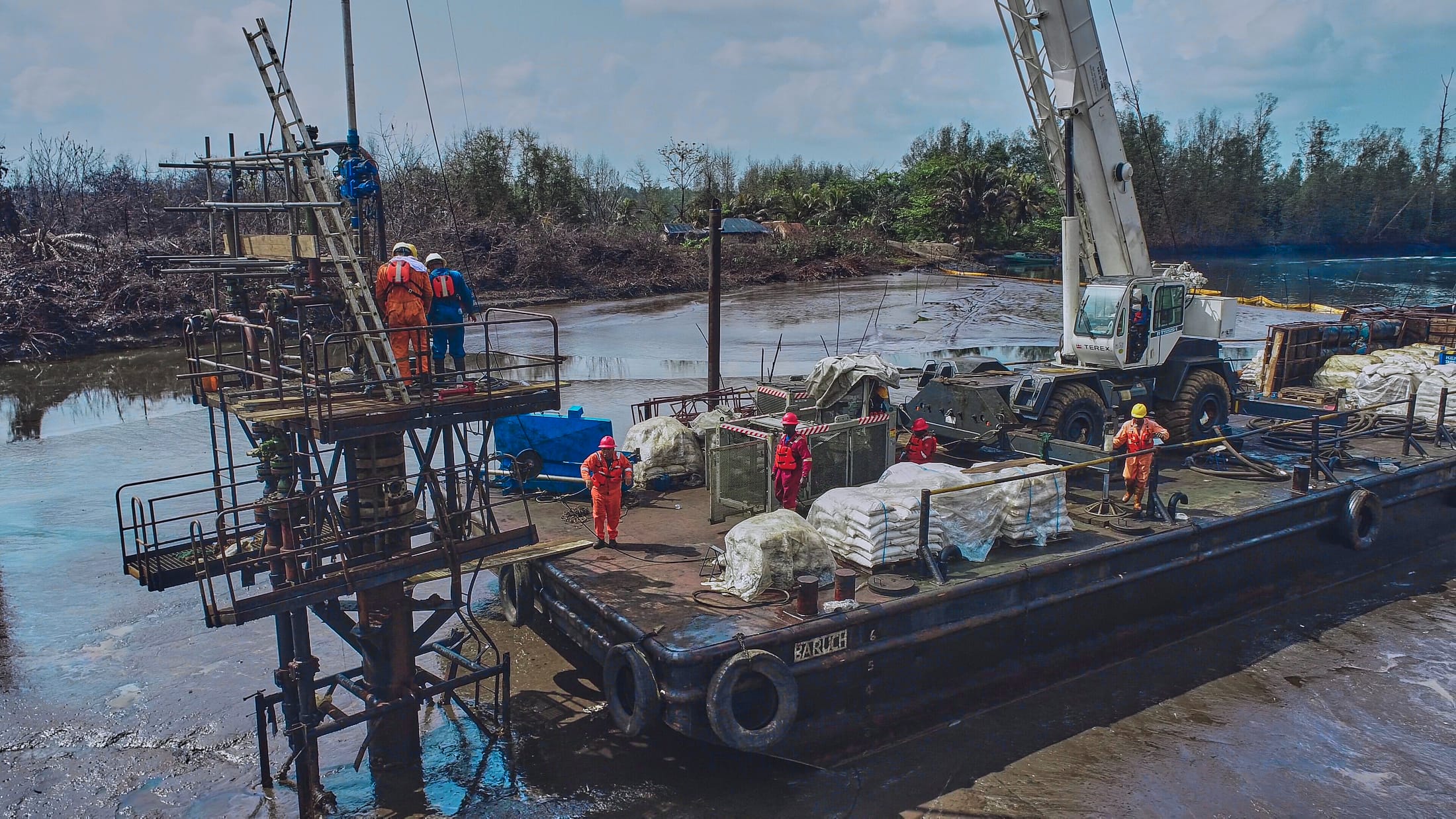 Aerial view of a spill containment boom and response barge on a Niger Delta waterway