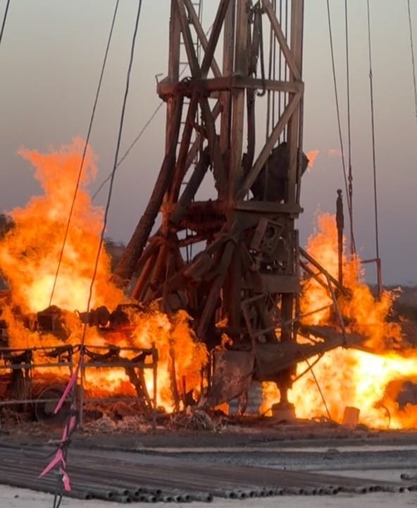 A tall gas flare burning against a dark night sky