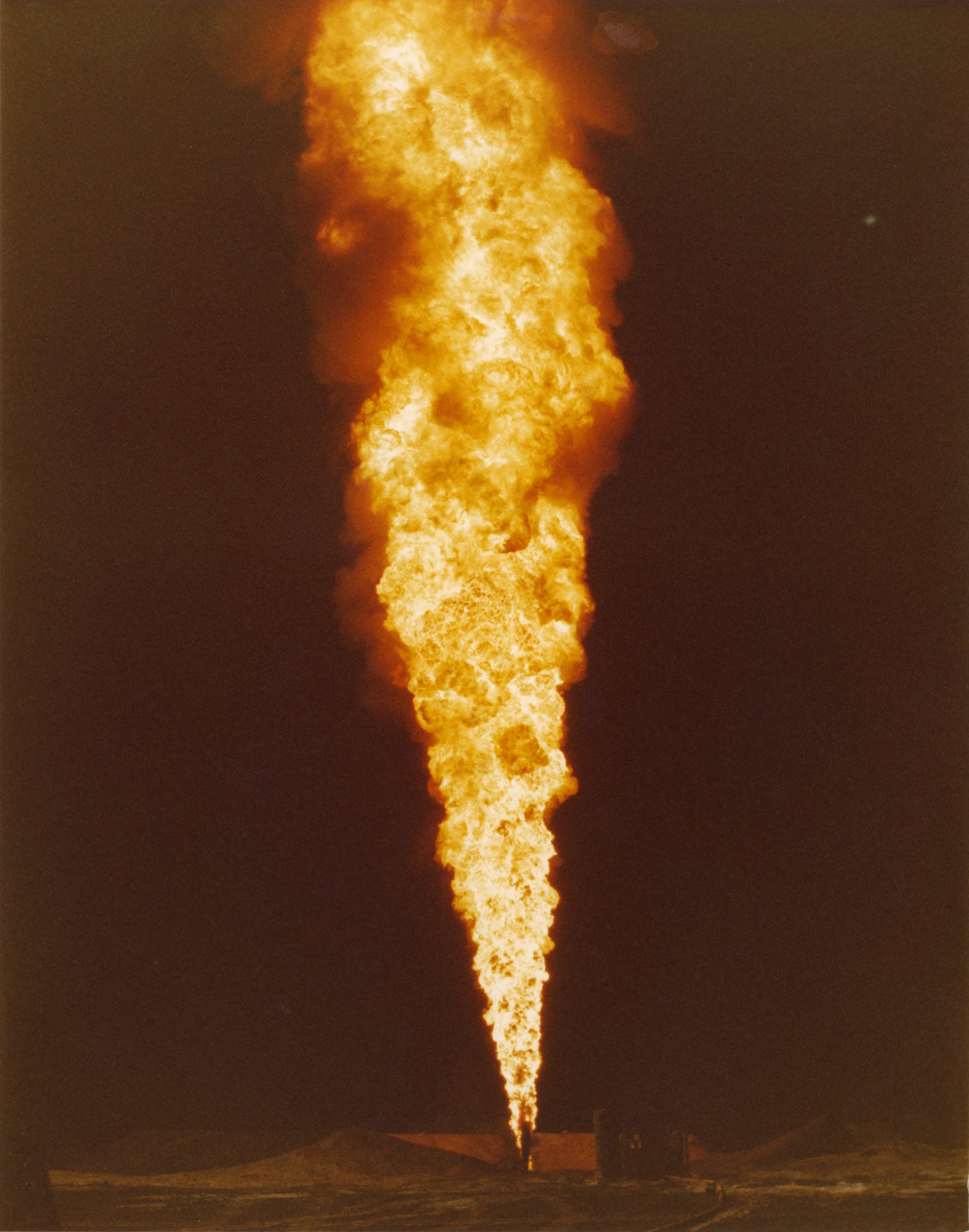 Flame and fluid erupting from a wellhead during an active blowout